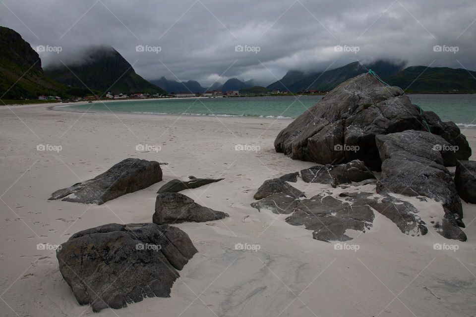 Rocks on a fjord beach and mountains in background 