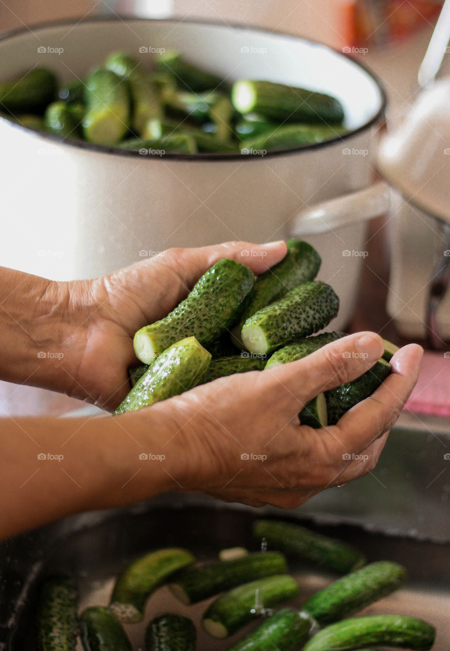 A woman washes cucumbers in the sink to make them pickle for the winter, autumn mood