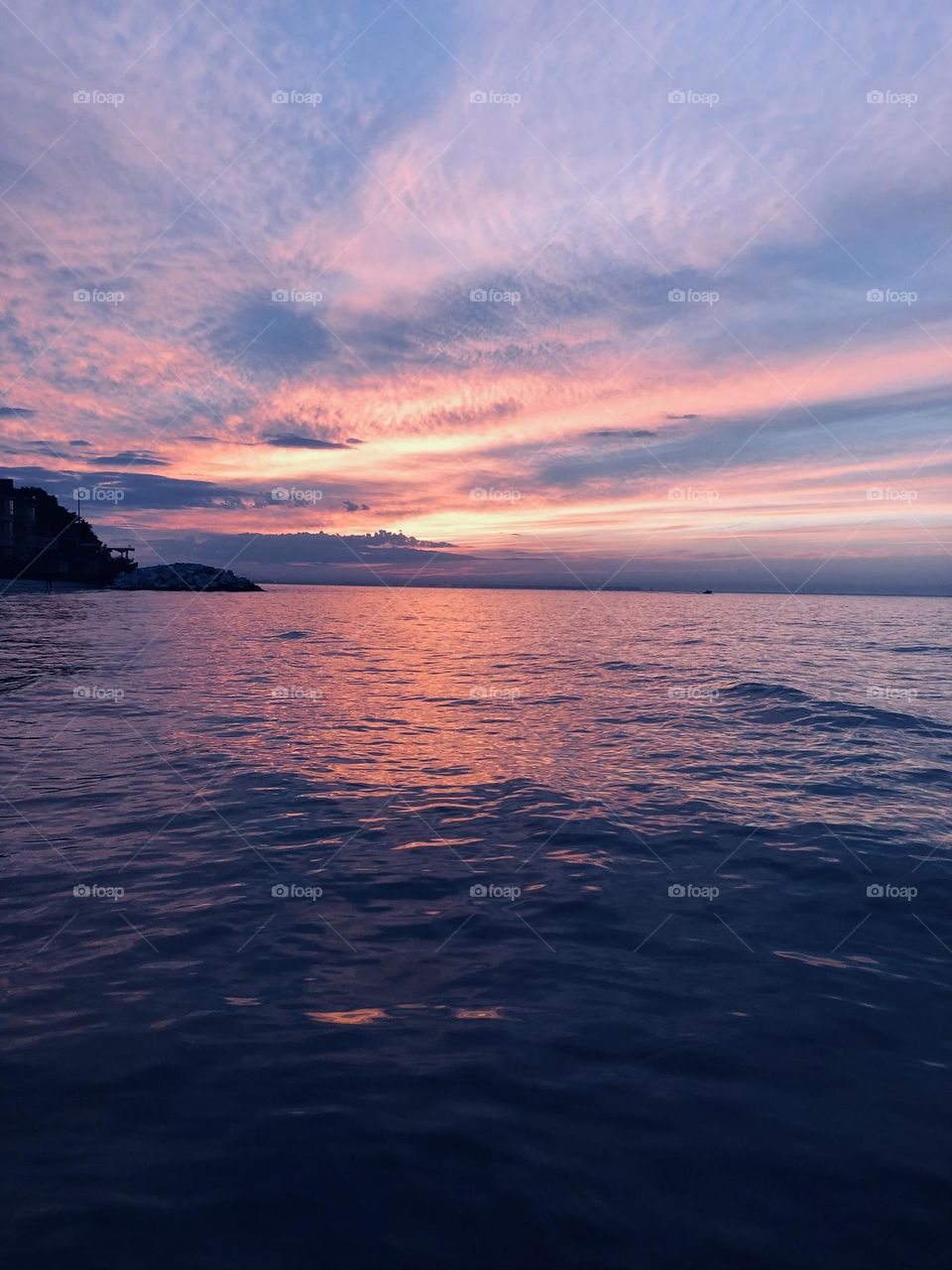 Watching the amazing sunset shine through the colorful clouds in Lake Michigan with tiny waves rippling in the lake. Am