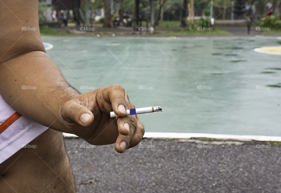 Hand holding a cigarette Background on basketball court