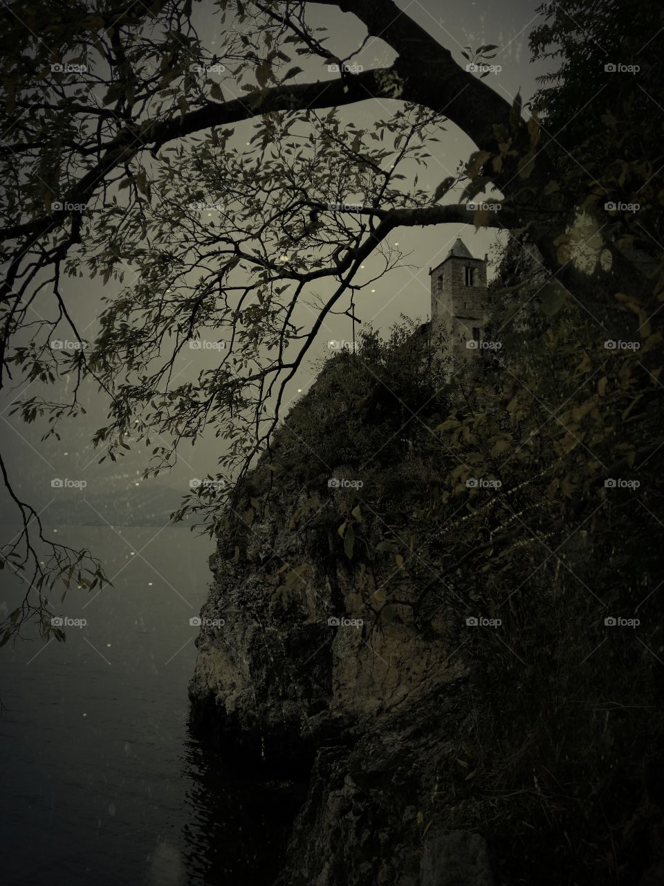 View through tree twigs on Hermitage of Santa Caterina del Sasso in the evening