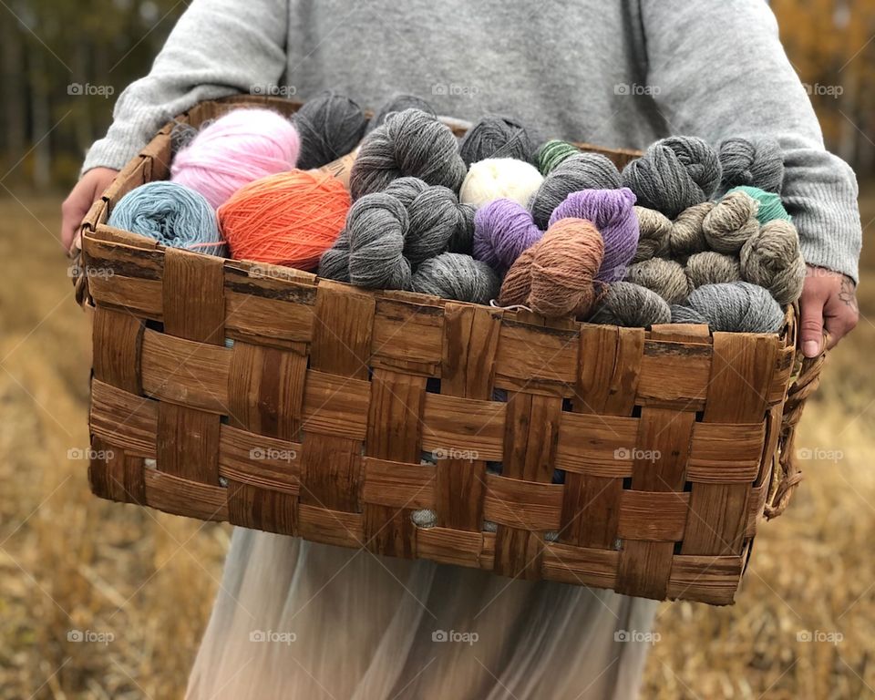 Woman carry yarns in field. Colourfull yarns in basket 
