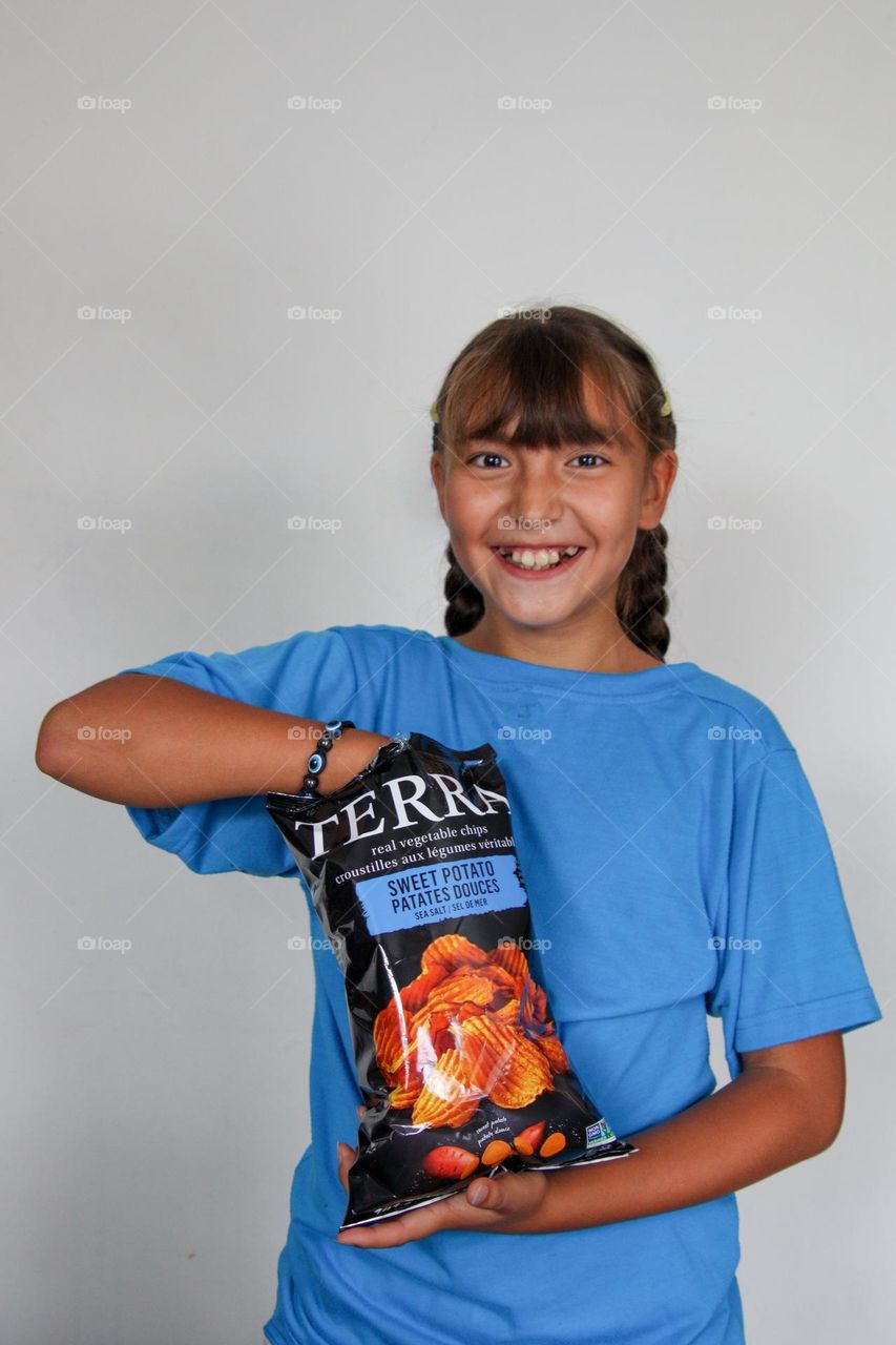 Cute happy girl with a bag of chips