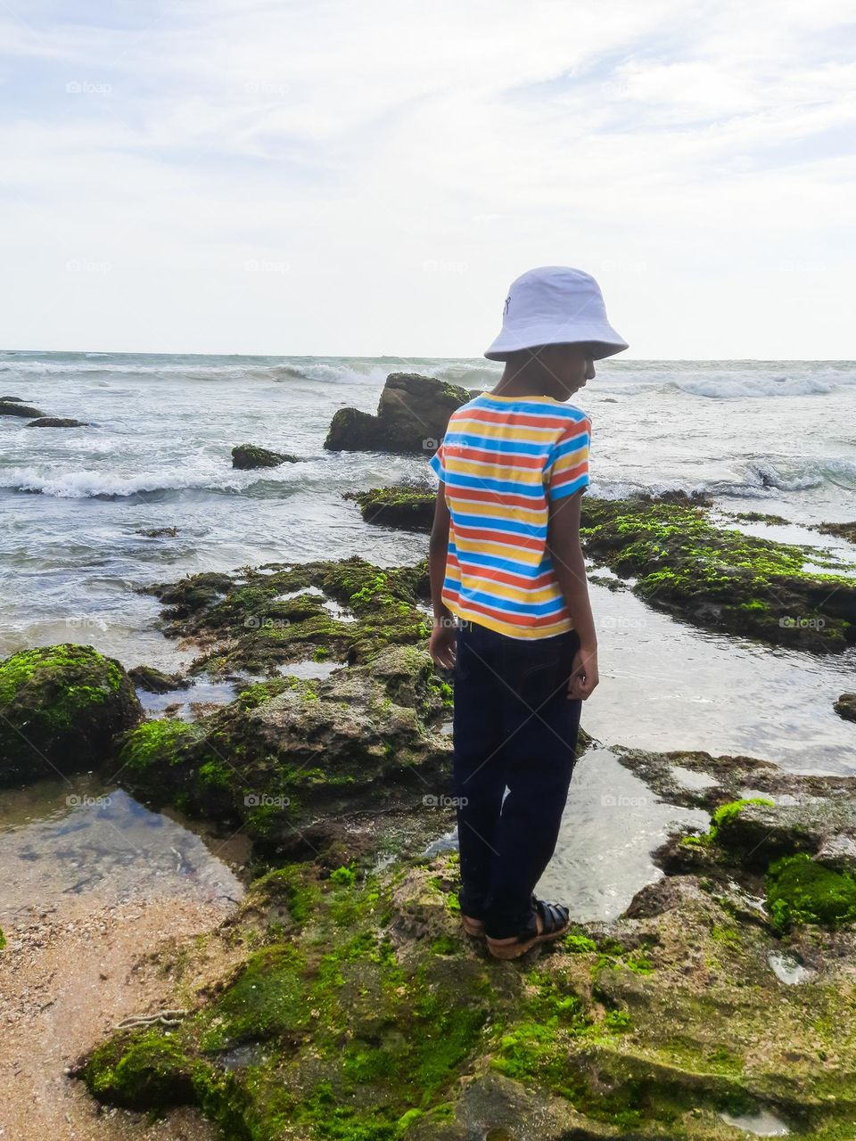 A boy standing on the rocks of the sea