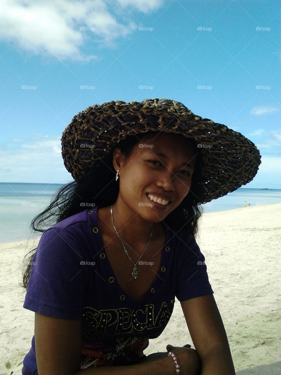 wearing a violet blouse and a native hat on the beach