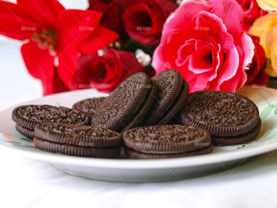 Oreo biscuits on a plate in the background with colorful flowers.