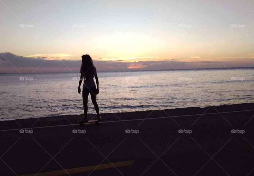 A girl on a skateboard at sunset