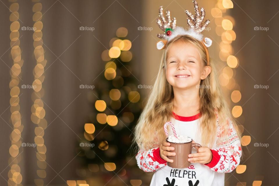 Cute little girl with blonde hair in Christmas pajamas 