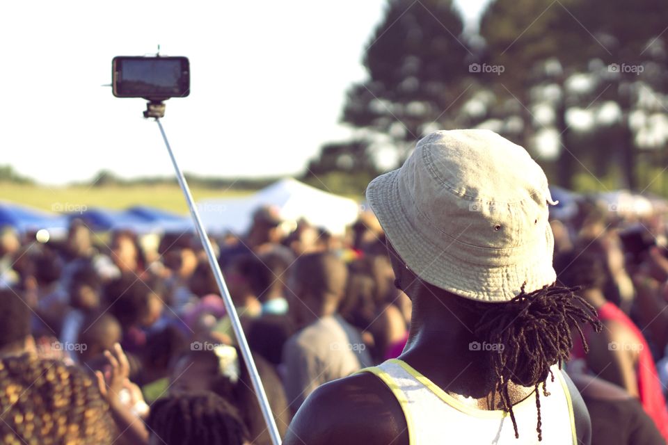 Selfie at a Concert. Man photographs himself and a crowd with a selfie stick. 