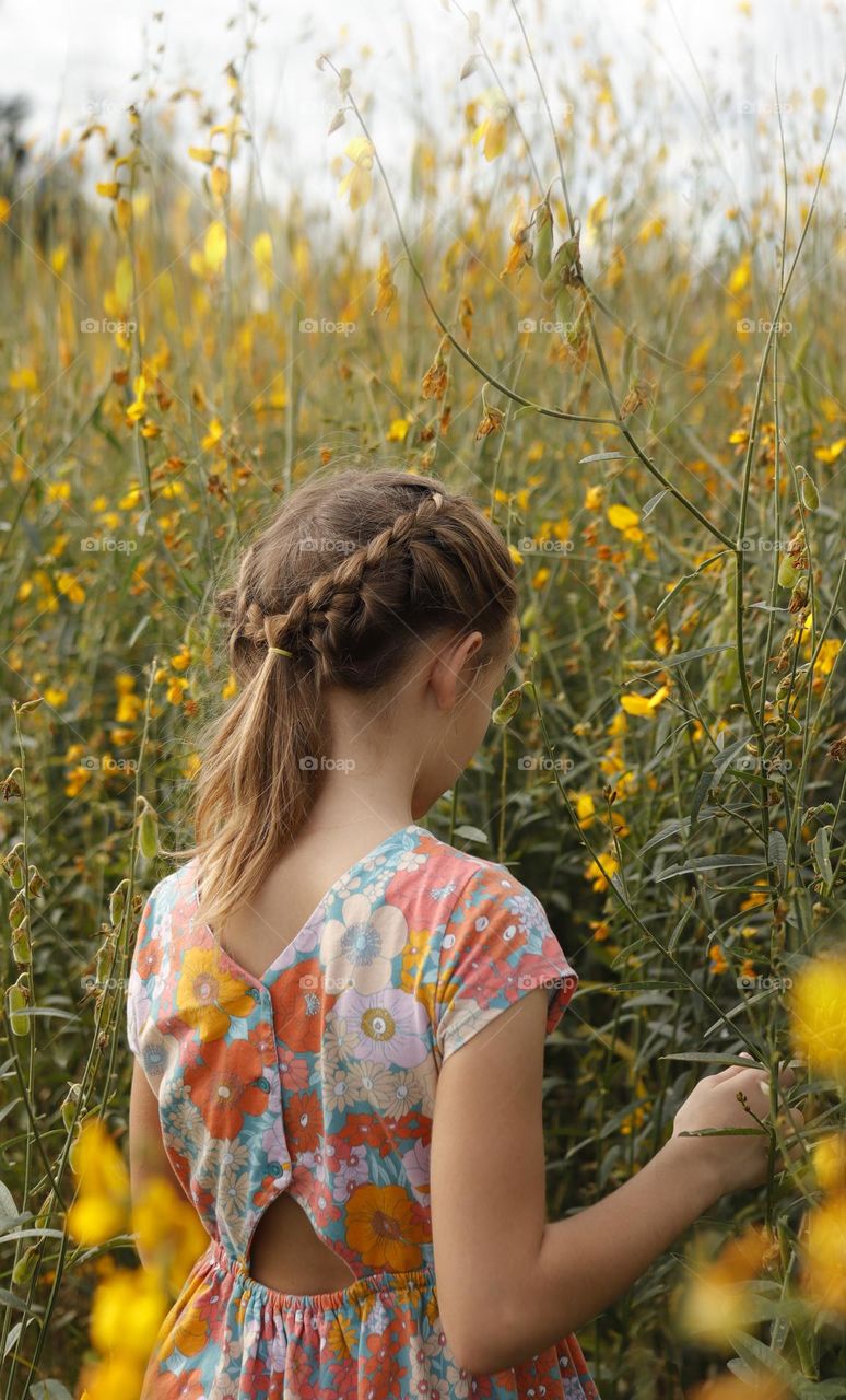 girl from behind in the field with yellow flowers