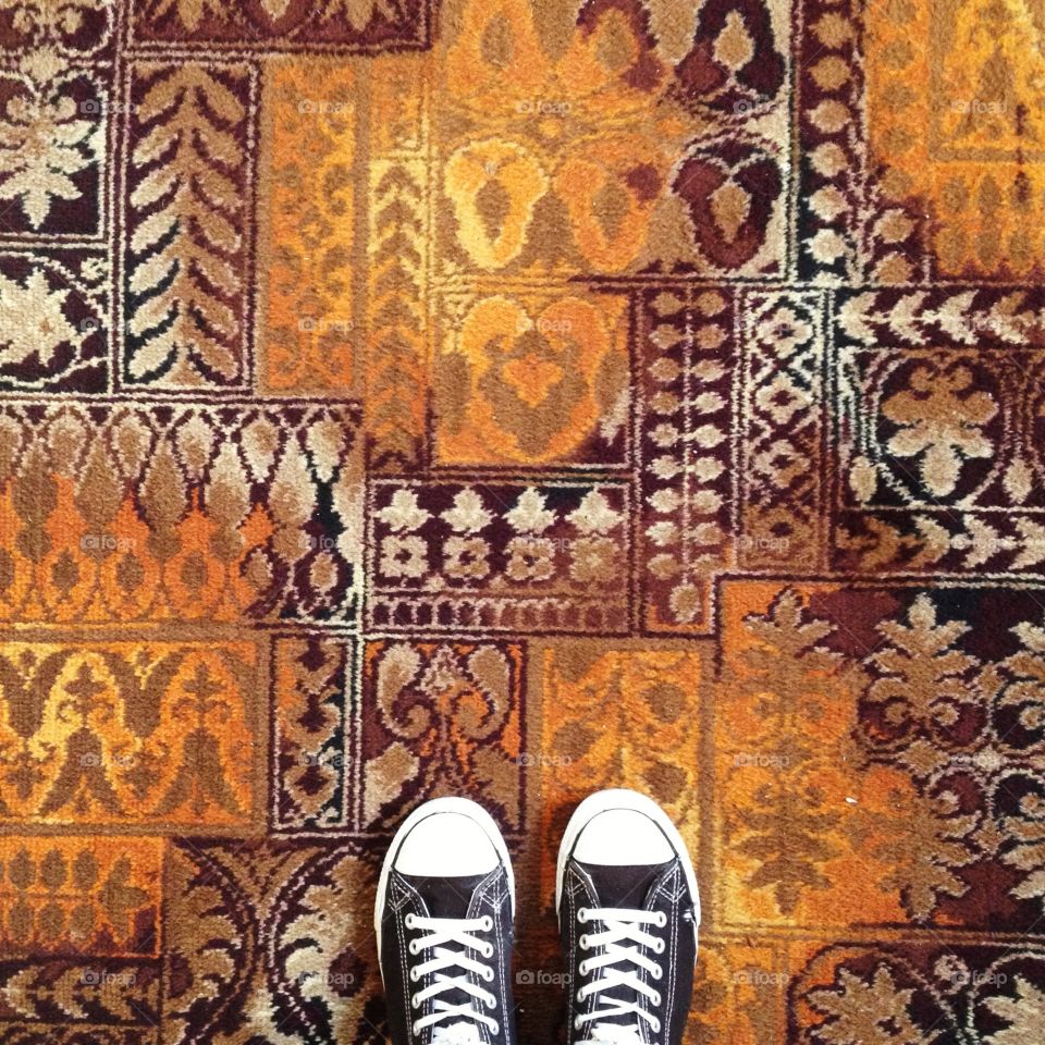 Feet and carpet. Looking down at sneakers and carpet