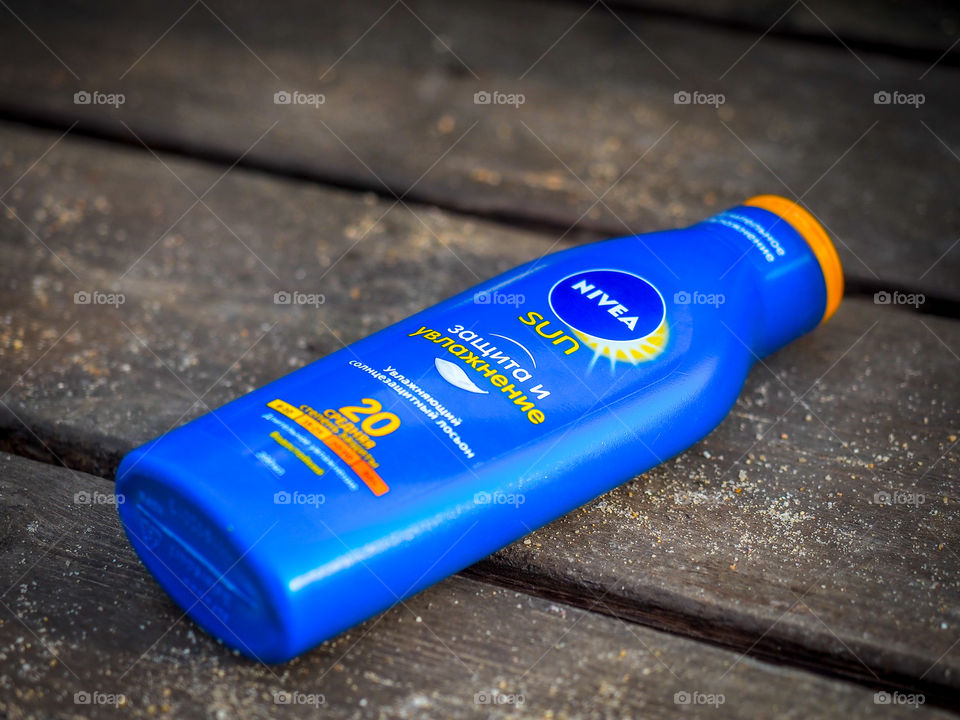 Moisturizing sunscreen lotion with an average degree of protection "NIVEA" on a sunny sandy beach.