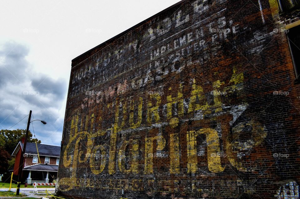 Old advertising on the side of a brick building tells tale of old business. 