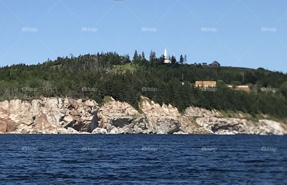 Landscape of church and buildings on rugged white gypsum coastline surrounded by trees above water. 