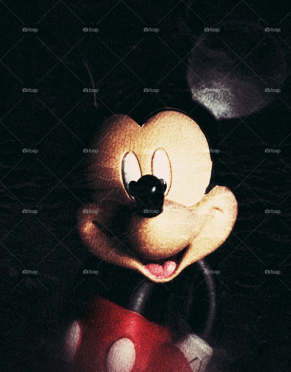 A portrait of Disney's Mickey Mouse on a dark background with a distressed, antique finish.