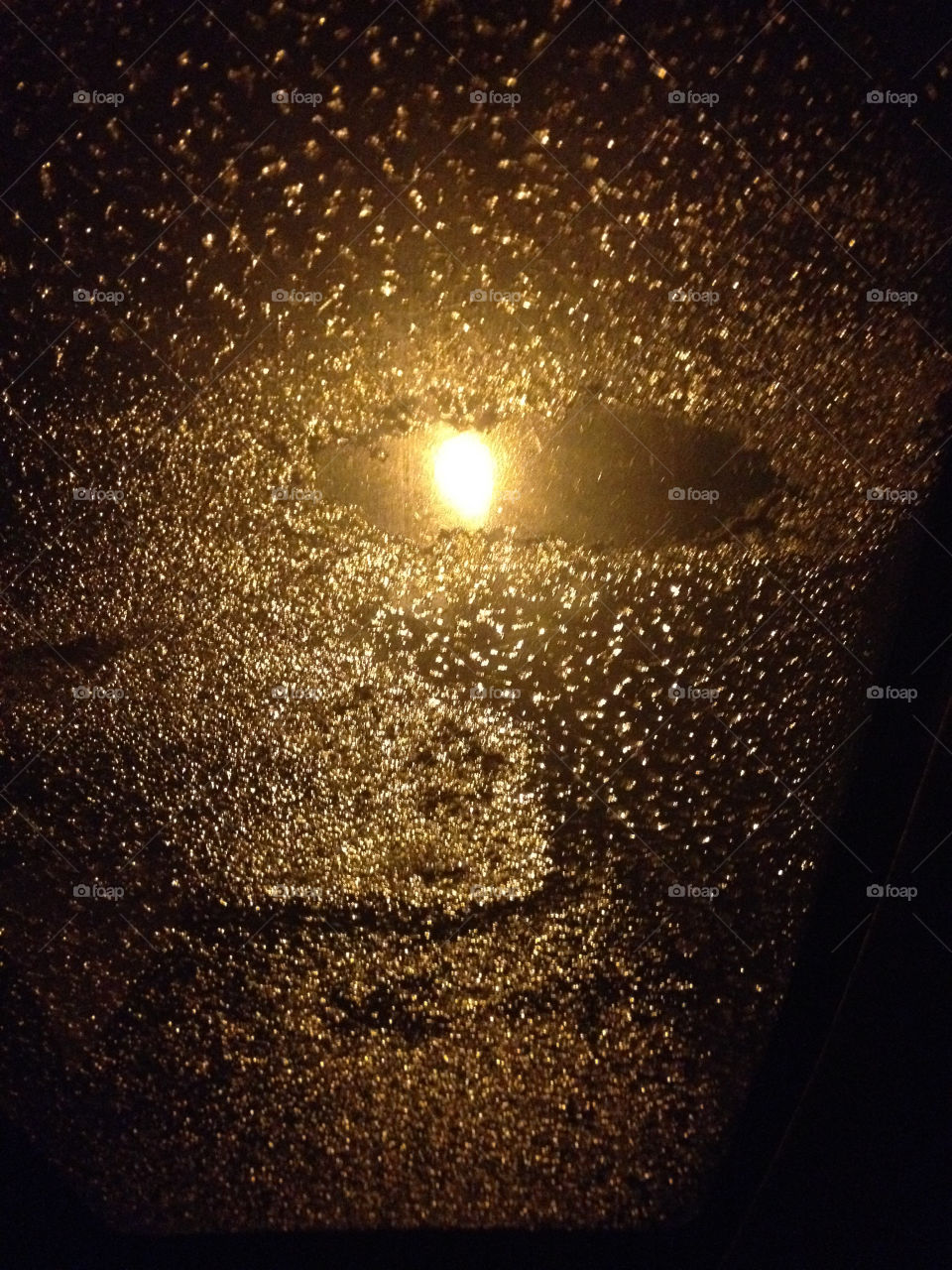 Snow on the roof window of a car in the form of a human face with lights in an eye