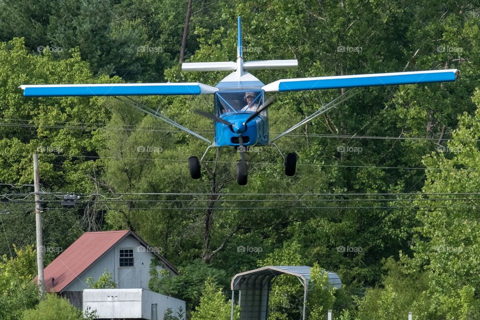 Foap, A to B: A pilot comes in for a landing, which requires clearing the tree line, then the power lines, then the fence to land safely in the grassy runway in the pasture as long as the cows are out of the way. 