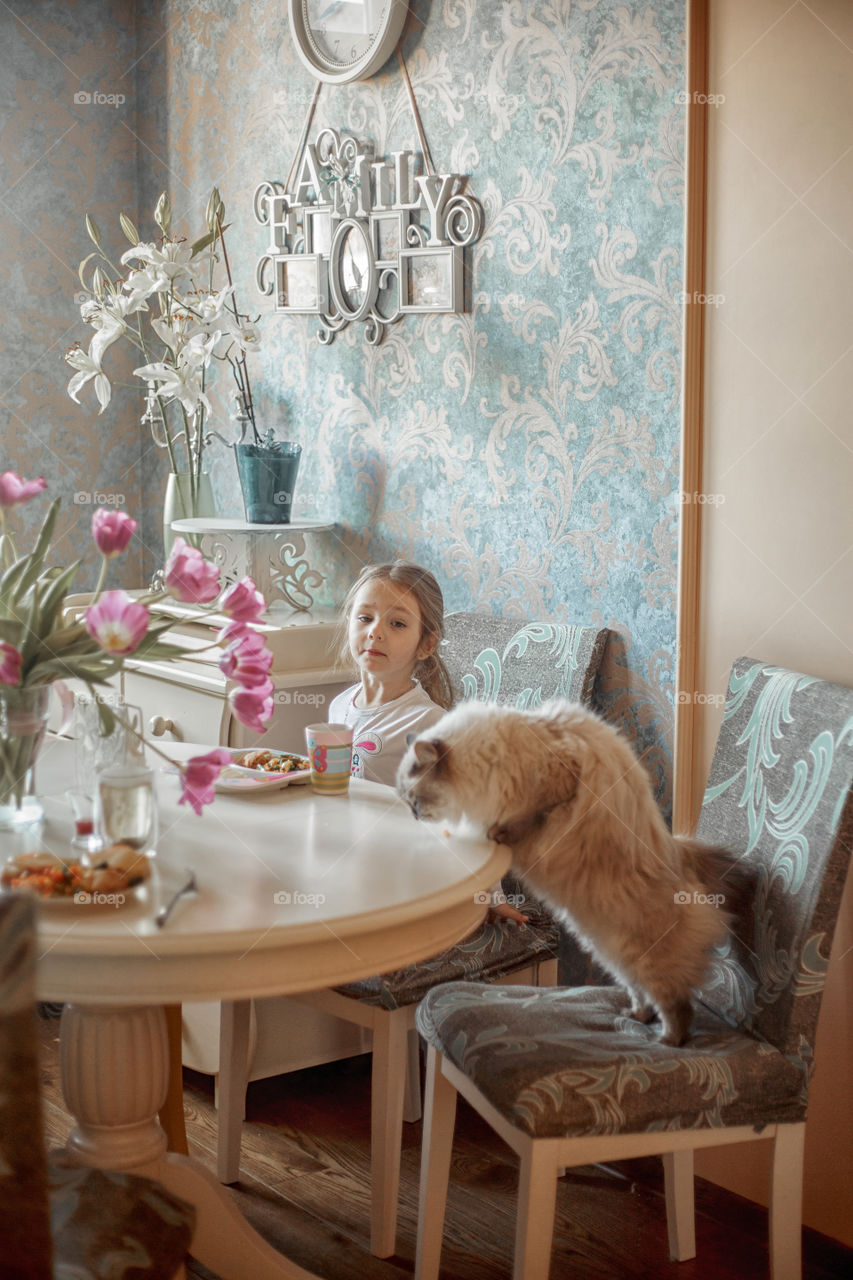 Little girl eating her breakfast in a light kitchen 