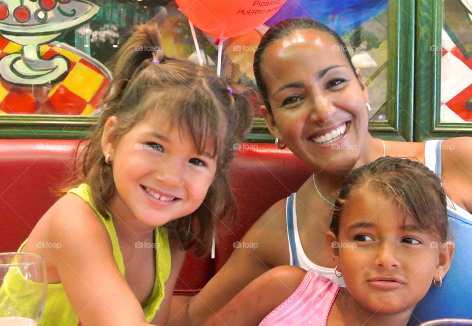 Smiling mother and daughters sitting in restaurant