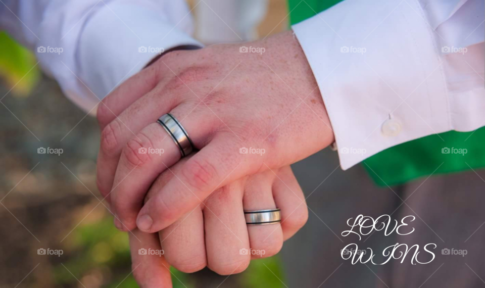 This is a beautiful photo of an LGBT+ couple holding hands with their rings and have gotten married after the same sex marriage law was passed, because love wins.