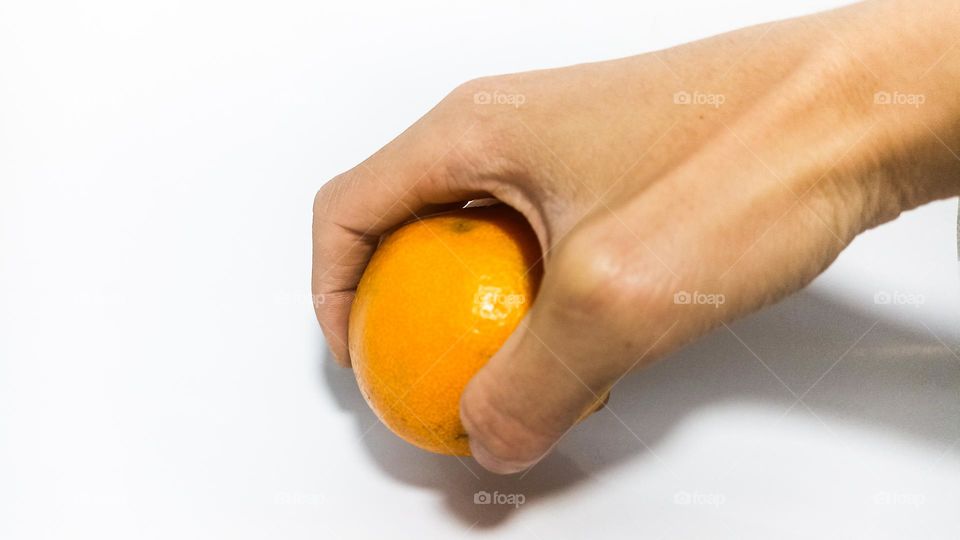 Human hand is picking up orange fruit on an isolated white background in eye level view