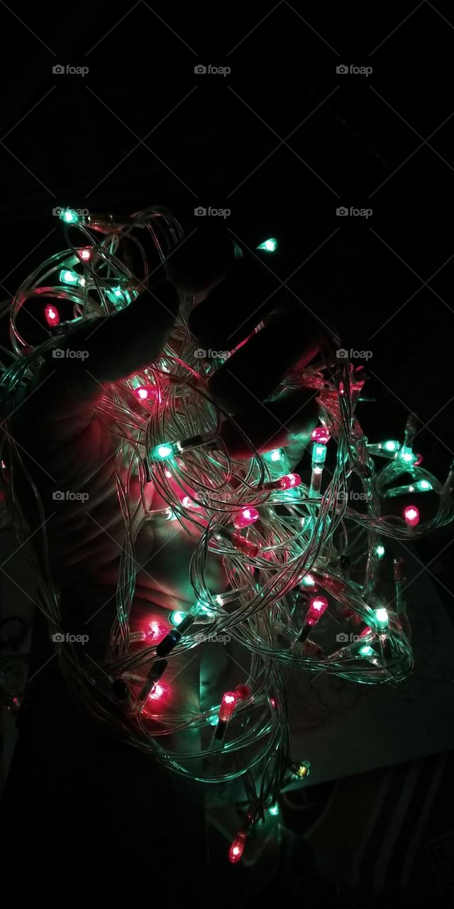 Holding colorful celebratory lights that glow in the dark.