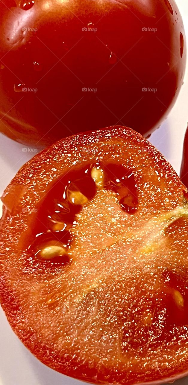 The photo shows a tomato cut into two halves.