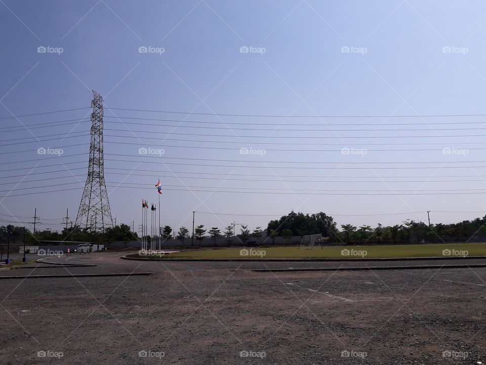 Football field near high voltage pole with blue sky day