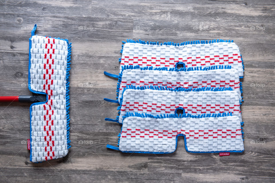 Flat lay of an O-Cedar mop and microfiber mop head refills on a hardwood floor