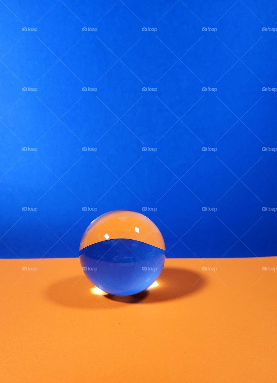 Orange and blue complementary colours flatlay composed with orange and blue papers and a crystal ball