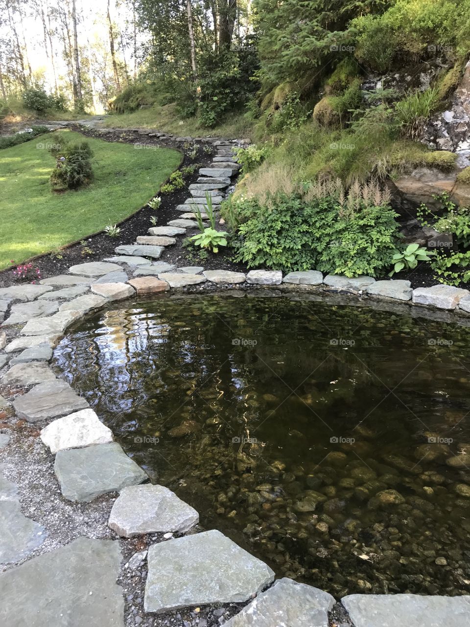 A pond with big stones around in Norway. A path goes further up from the pond.  