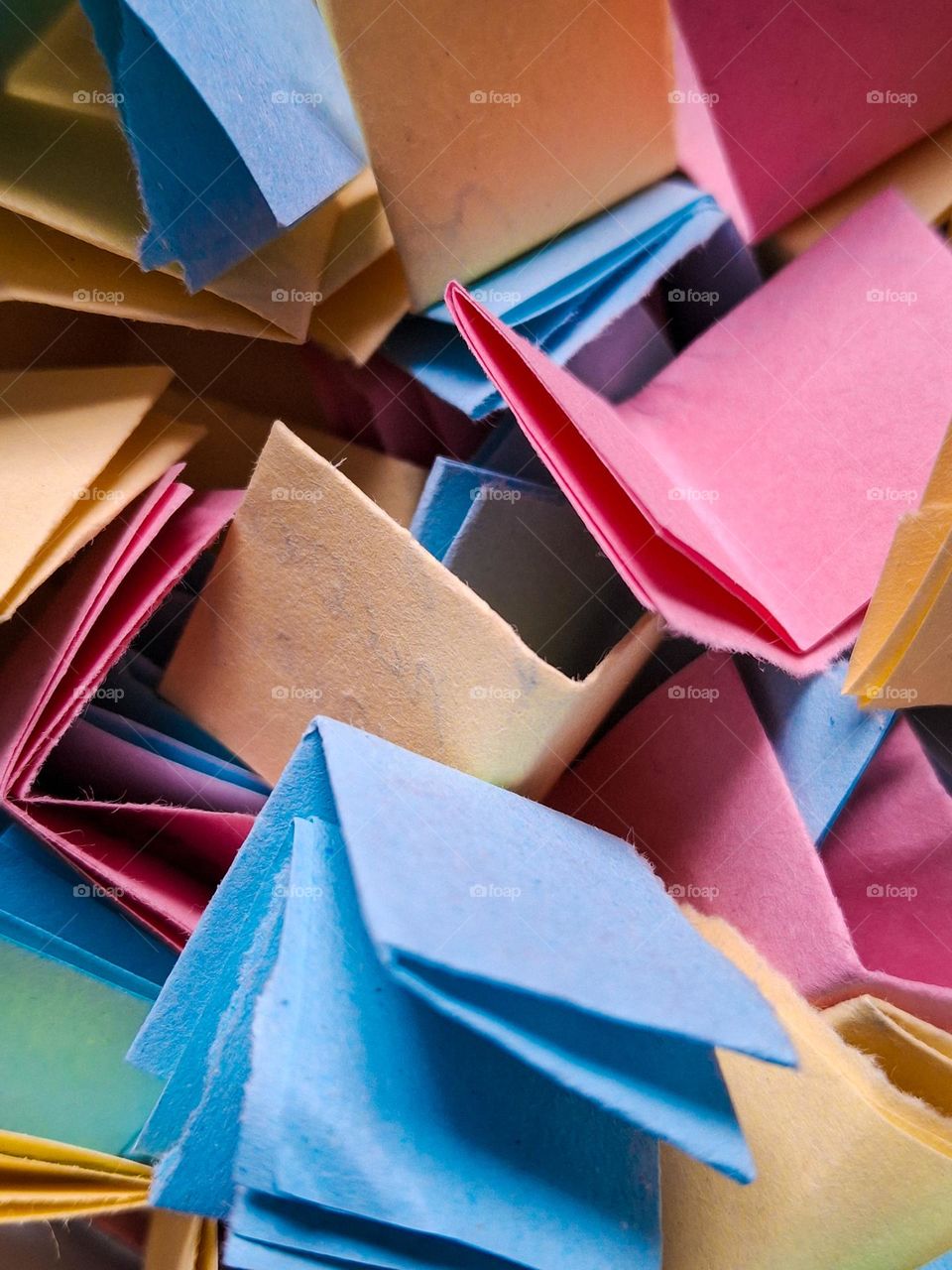 macro photo of small notes written on colorful note papers in blue, yellow and pink colors