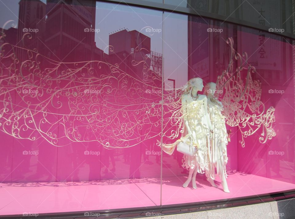 Elegant White Fashion Display behind Glass Shop Window, Ginza, Tokyo, Japan.  Winged Mannequins against Bright Pink Background