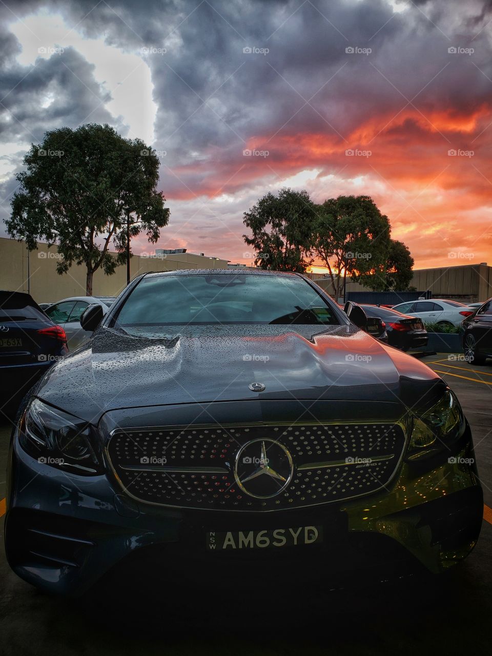 Mercedes Benz car covered with light drizzling of rain. Dramatic and intense cloudscape above.