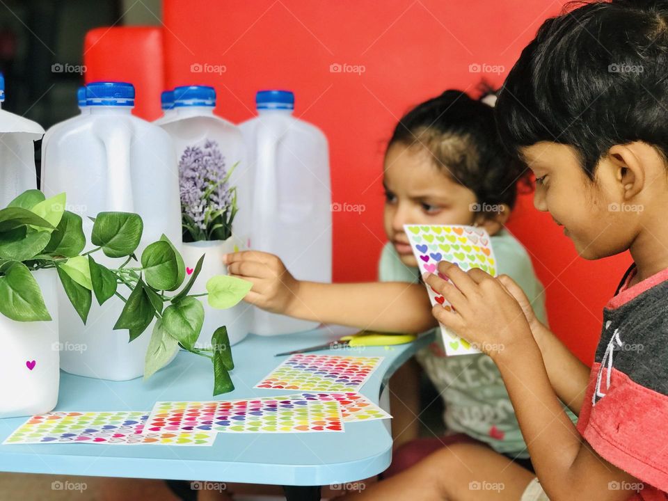 Children doing craft making flower pots from plastic milk bottles.