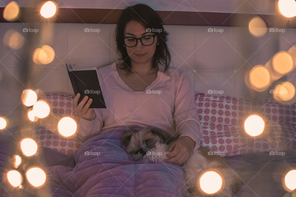 Girl reading with her dog before sleep