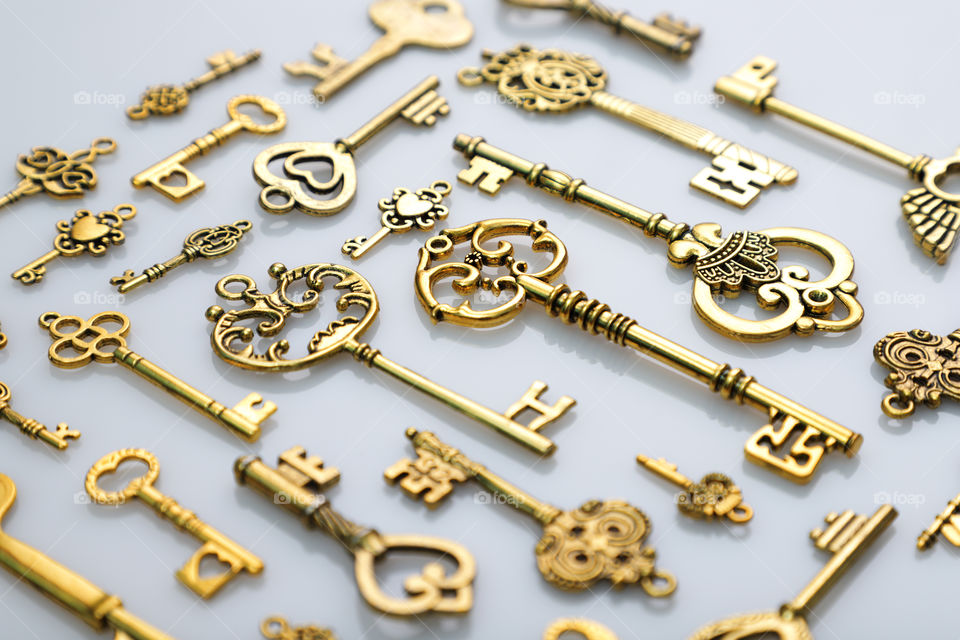 Beautiful antique golden keys on white reflective background