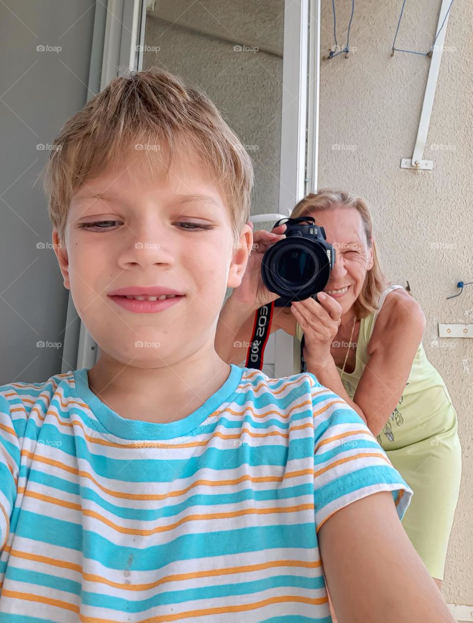 A boy takes selfie with his grandma in background