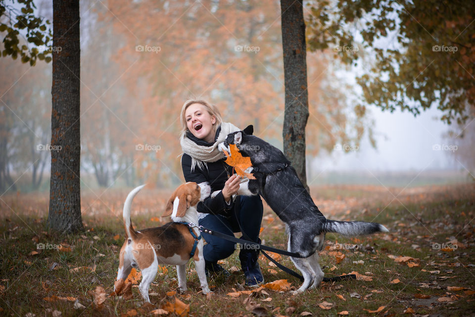 Woman with two dogs having fun autumn park