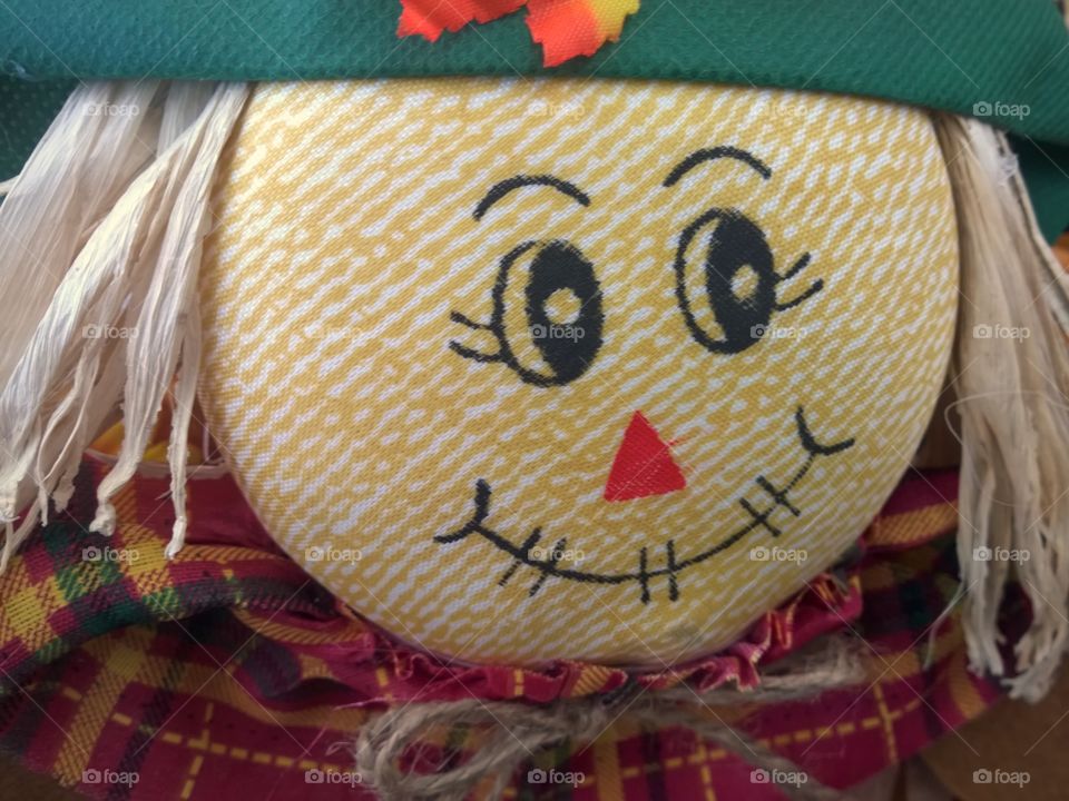 Scarecrow decorations, smiling and looking to the left.