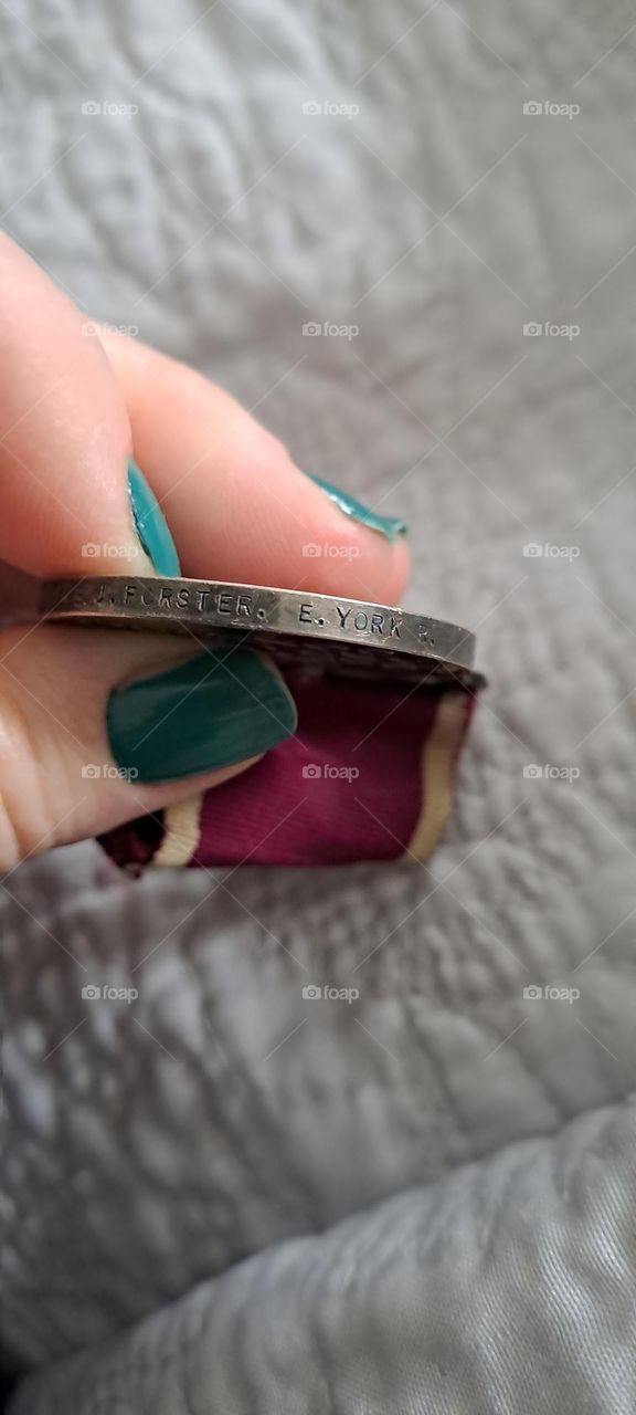 medal held by ladies fingers nailvarnish discription