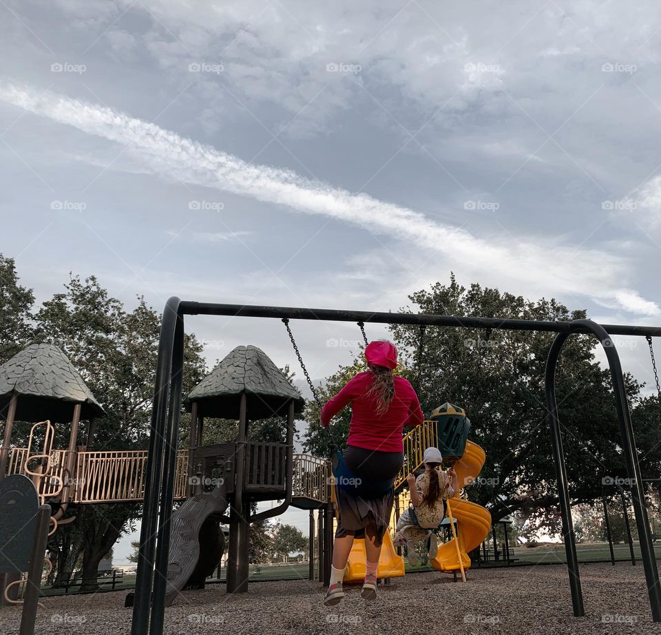 Playground Where The Children Are Playing On The Swing Set Under The Cloudy Sky Have Fun.