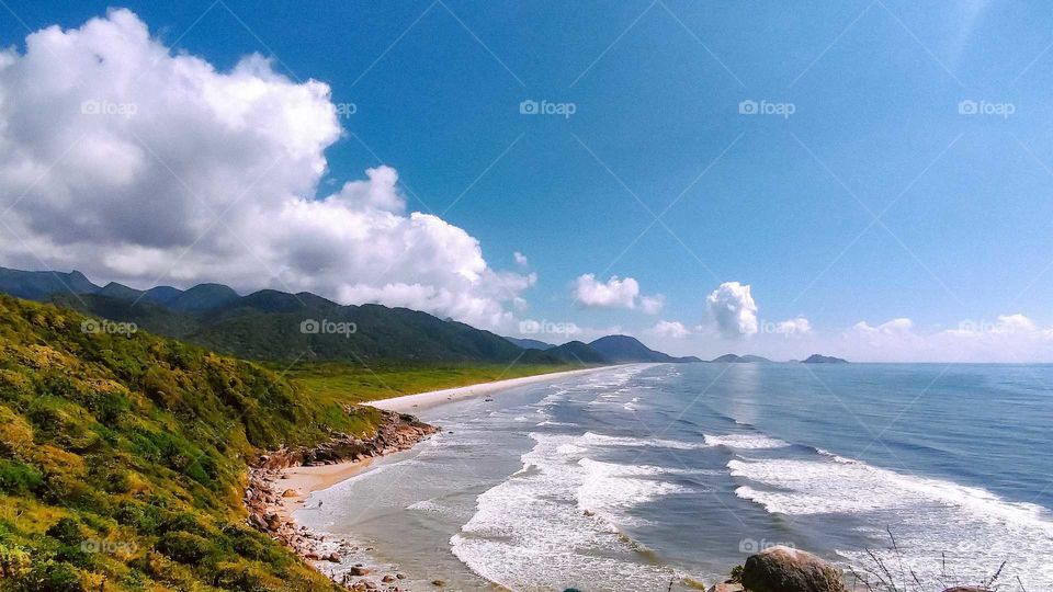 Beautiful Brazilian Beach, at Ilha do Cardoso, Cananéia. Long Beach, sunny day and people hiking in the mountains.