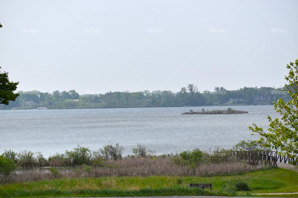A beautiful lake with an island is overlooked by surrounding neighborhoods and a park