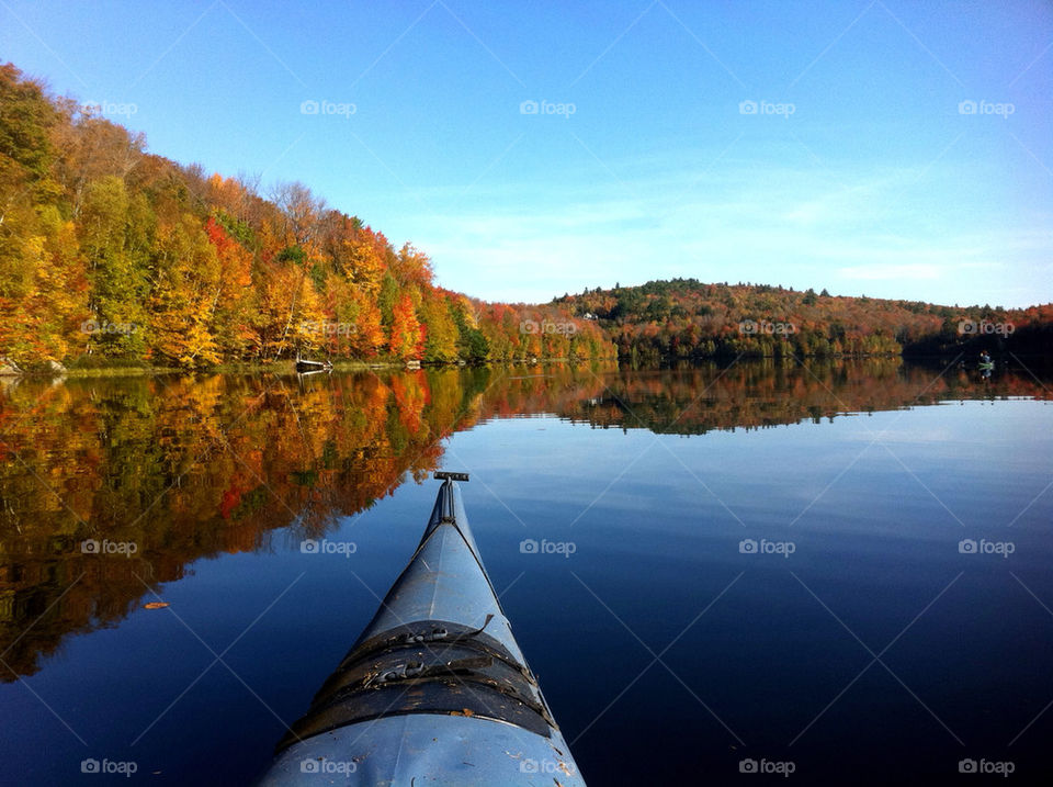Reflection of autumn trees on lake with bow of kayak