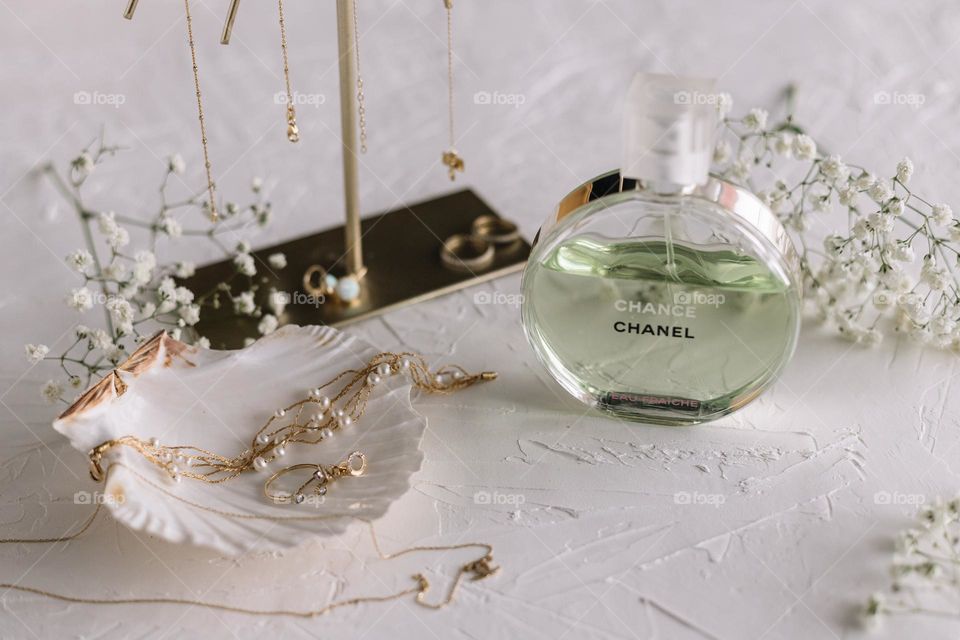 Delicate arrangements with jewelry and an enchanting Chanel perfume on a white background.