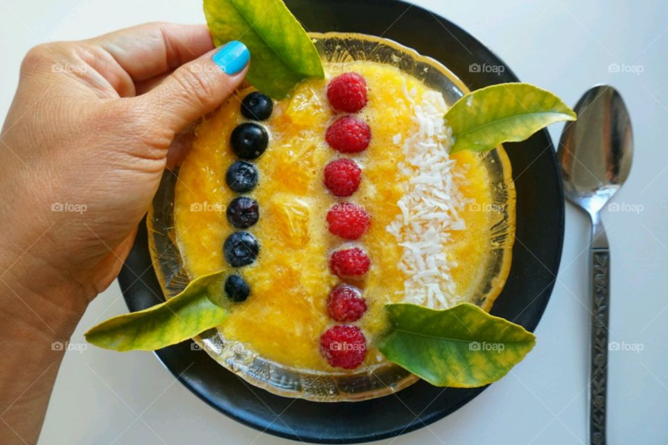 Fresh fruit smoothie - orange smoothie topped blueberries,  raspberries and diced coconut