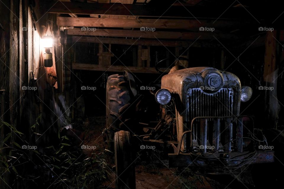 Foap, Light: Natural vs Artificial - Light from a lantern illuminated an antique tractor resting in the breezeway of an old wooden barn. 