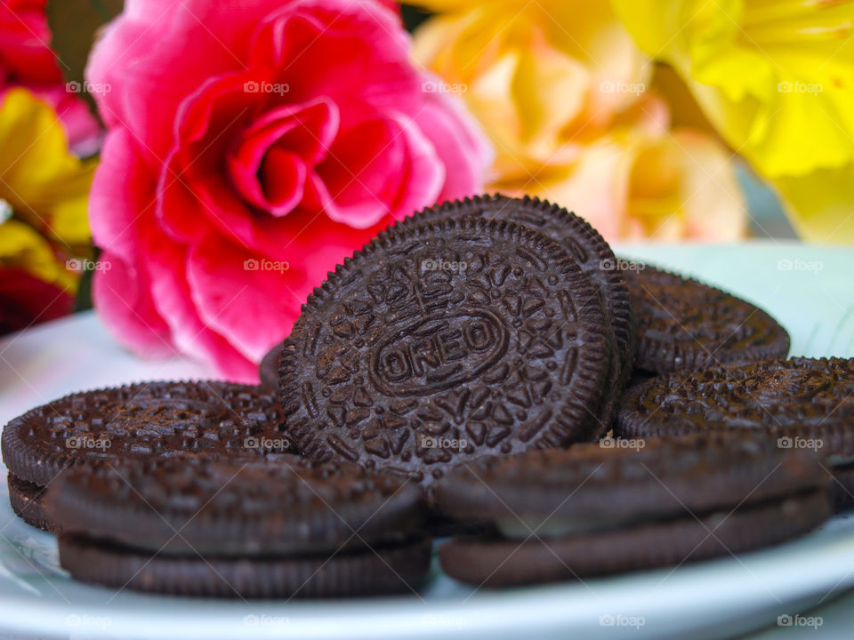 Oreo biscuits on a plate in the background with colorful flowers.