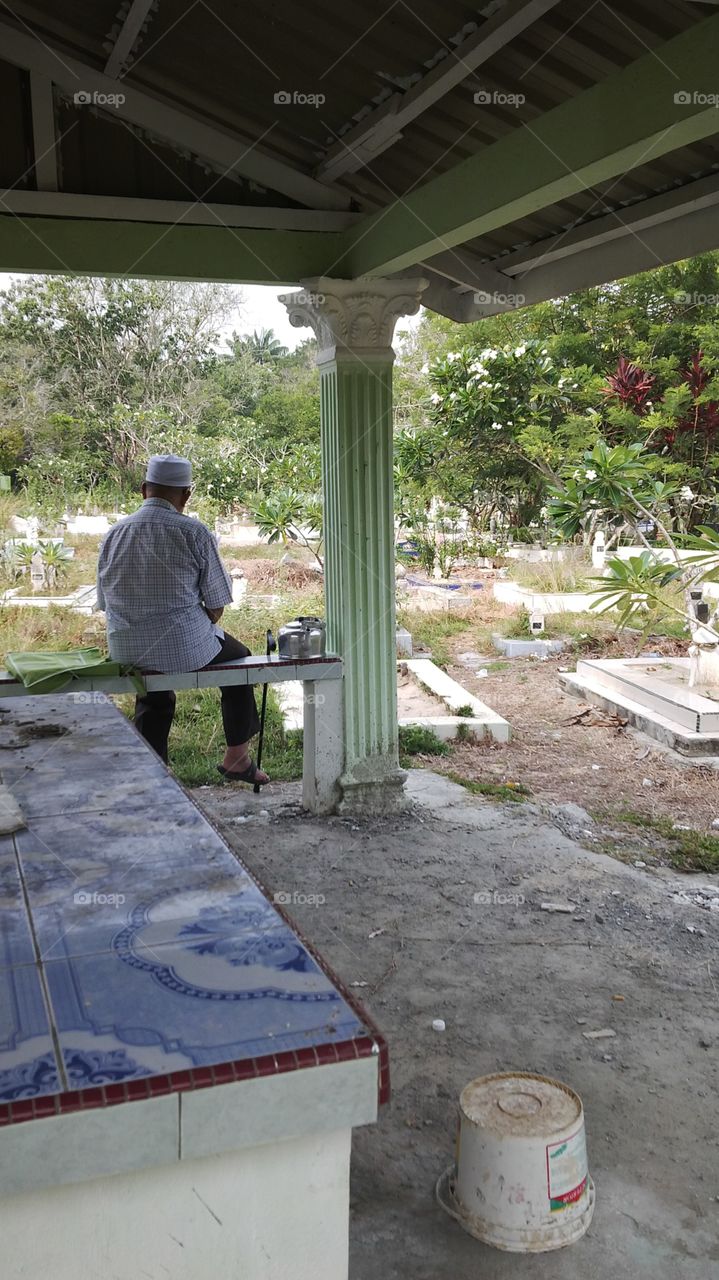 Rear view of man sitting in cemetery
